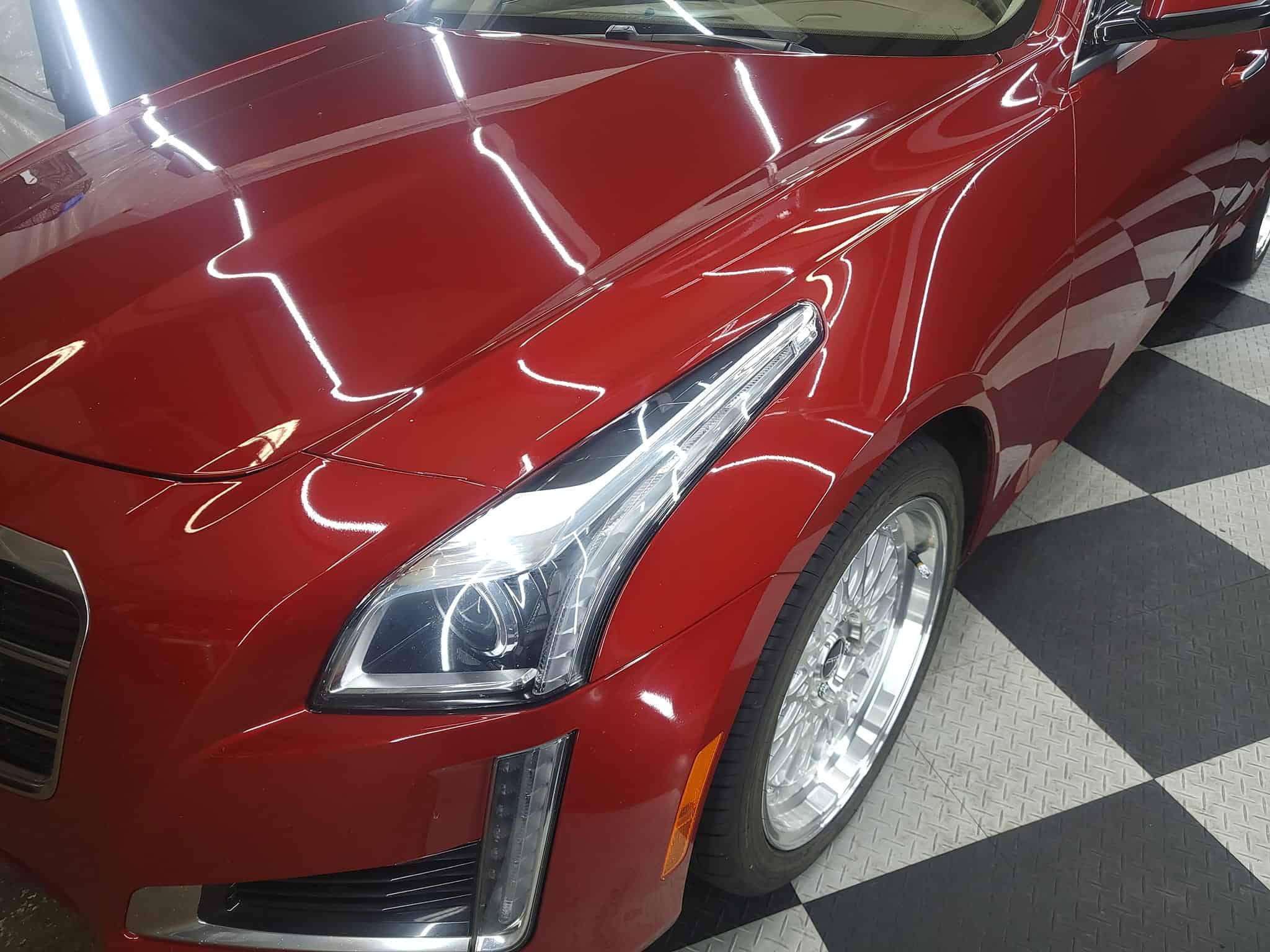 a red cadillac is parked in a showroom.